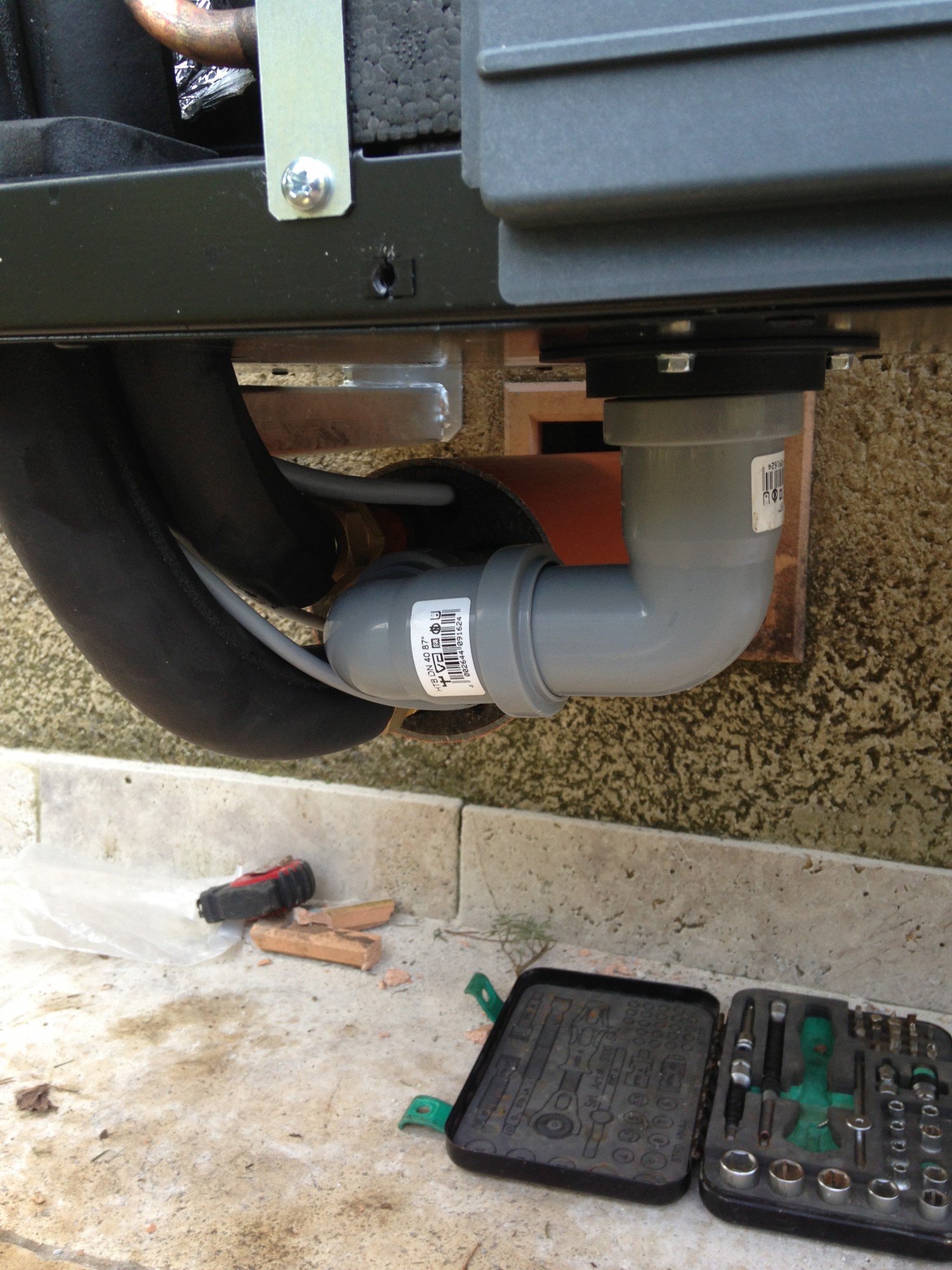 Montage avec passage de mur assurant une protection antigel et permettant d'évacuer les condensats à l'intérieur